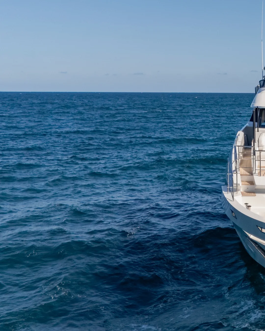 Open sea, a yacht's hull at the edge of the frame.